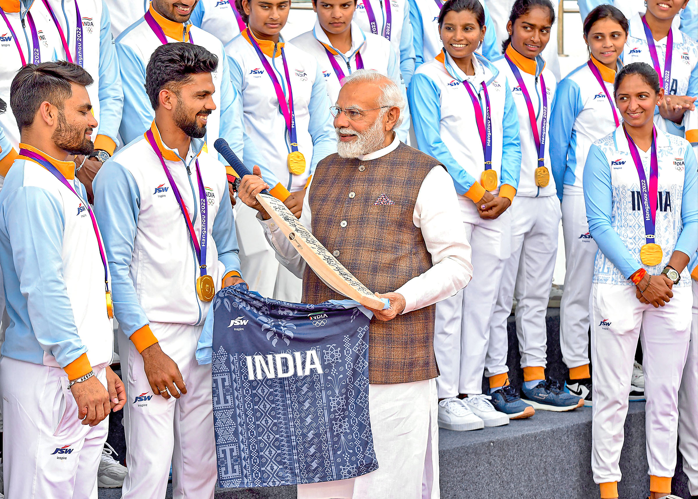 Prime Minister Narendra Modi being presented a bat and India ti-shirt as he meets with gold medal winning cricket teams and other Asian Games medal winners.