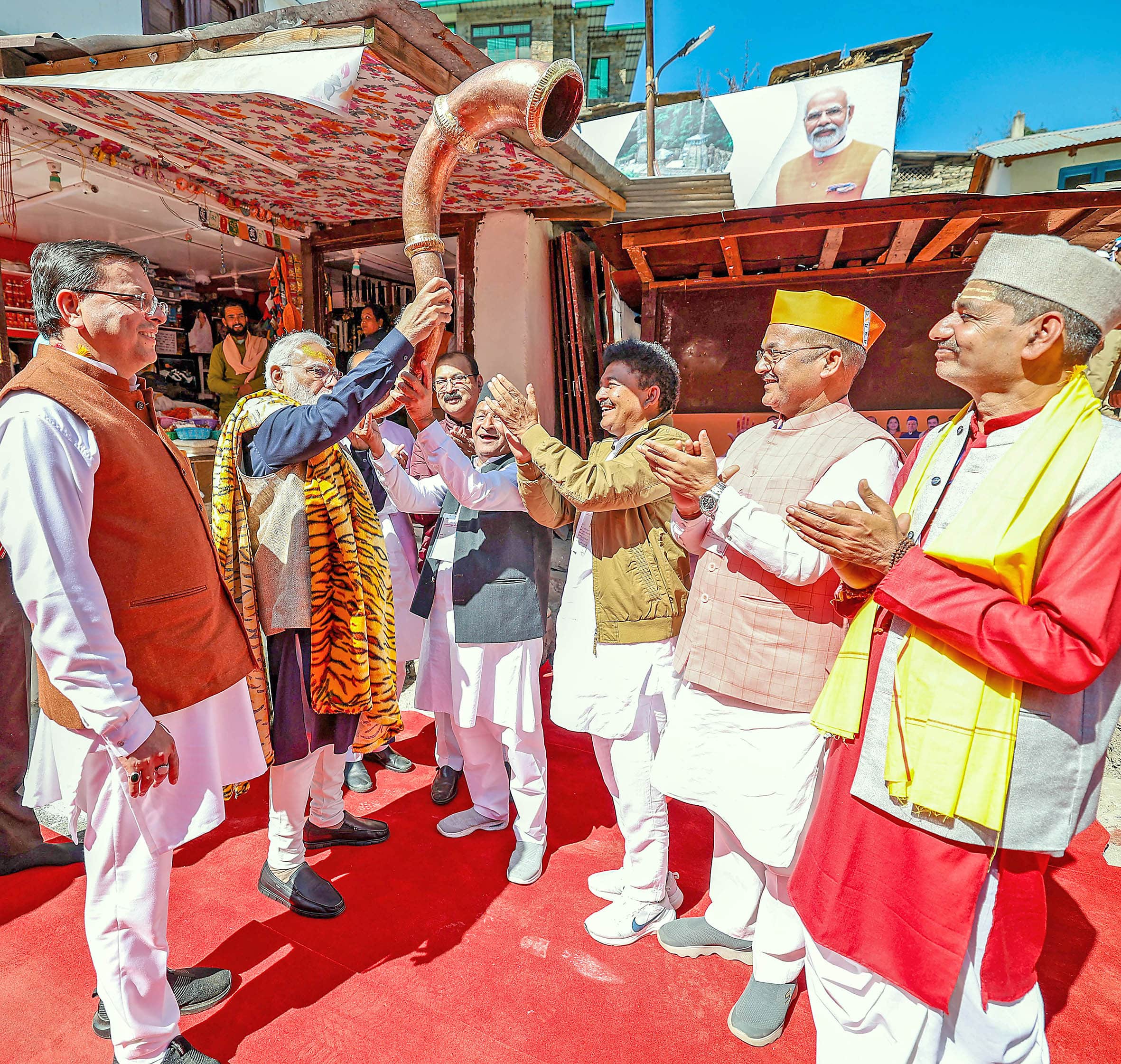 PM Narendra Modi blows a trumpet as Pushkar Singh Dhami and others look on, during visit to the Jageshwar Dham in Almora.